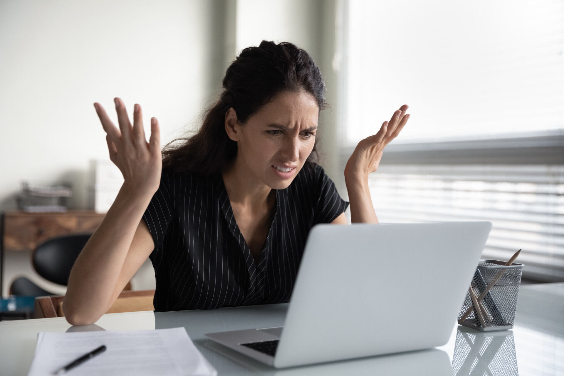 A woman with a frustrated look on her face looking at a laptop